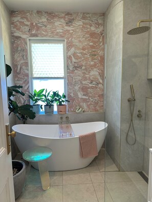 A modern bathroom with a freestanding bathtub, a glass shower enclosure, and a window with plants. - Historical terrace house in the middle of Fitzroy (Fitzroy)