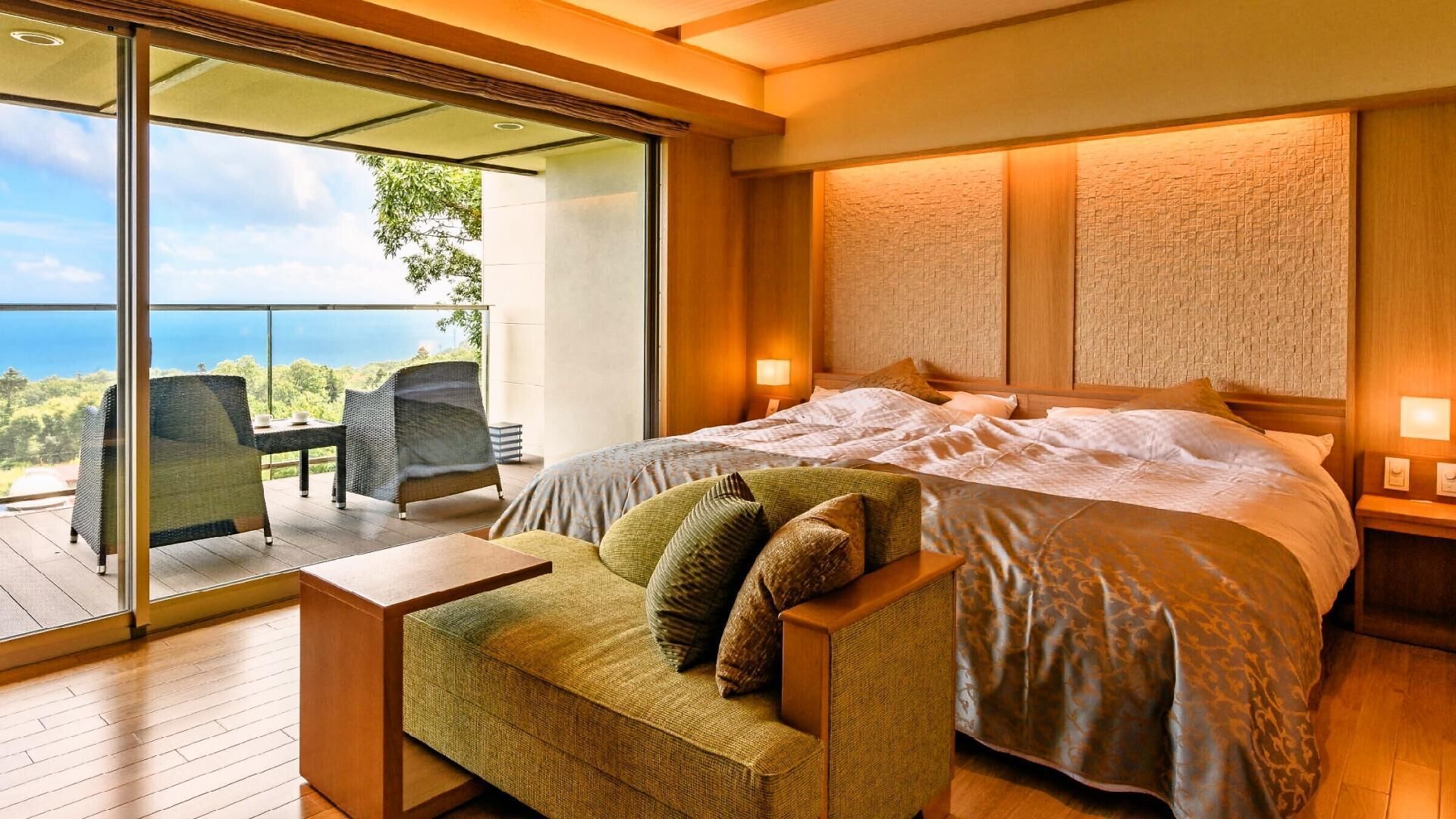 A bedroom with a large bed, a sofa, a table, and a balcony with a view.