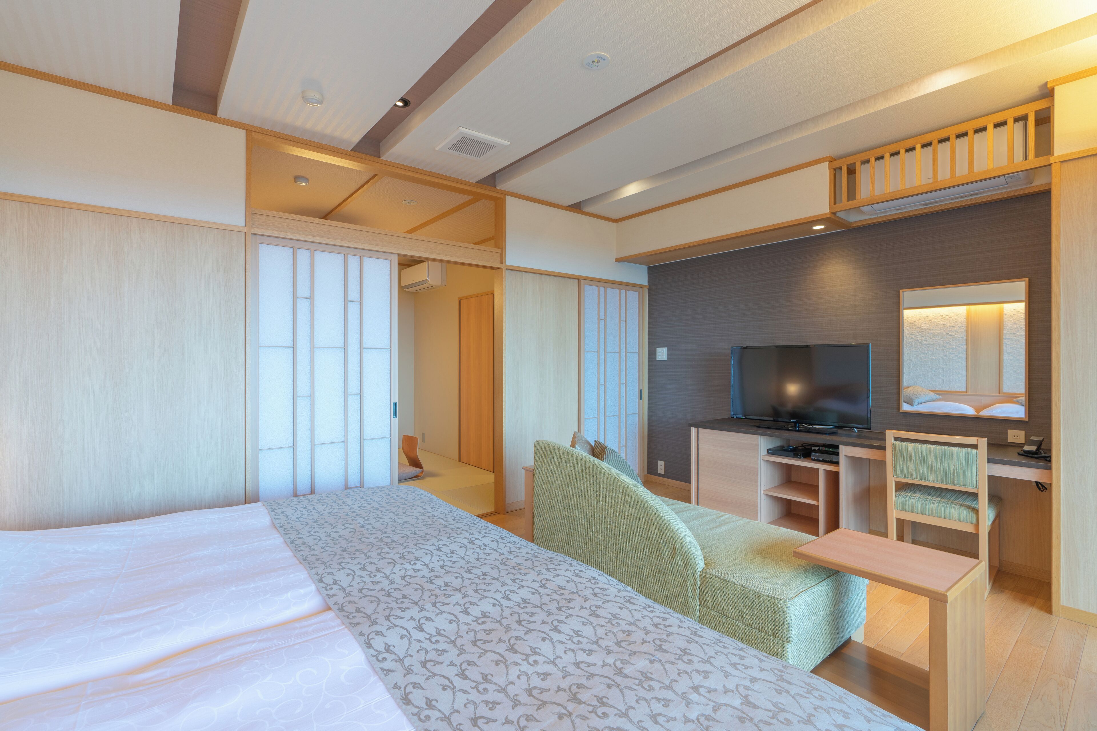 Una habitación de hotel moderna con una cama grande, un escritorio, un televisor y una zona de estar.