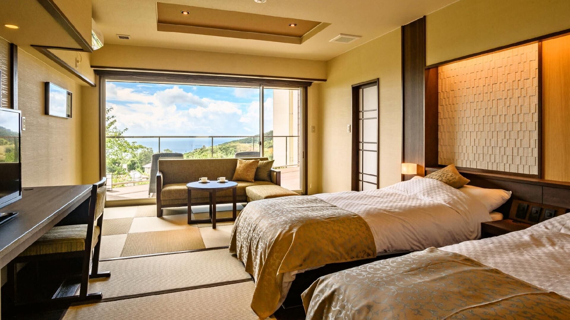 A hotel room with a balcony, a desk, two beds, and a view of the outdoors.