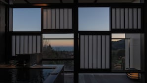 A room with a view of the ocean and hills, featuring a wooden deck and a small pool. - Omuro no Mori Gyokusui - 13 years or older - (Ito)
