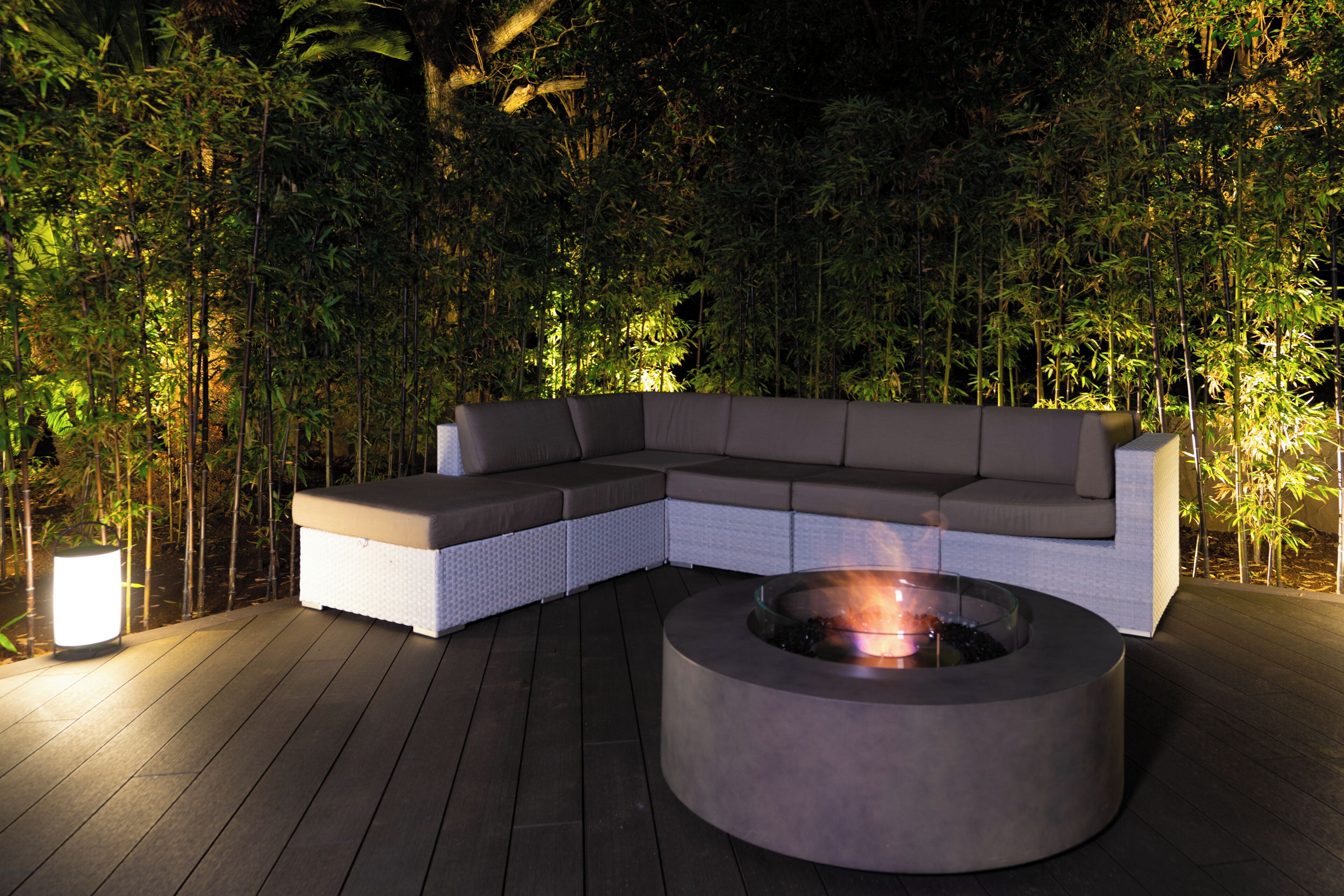 A modern outdoor seating area with a built-in fire pit and a white cushioned sofa.