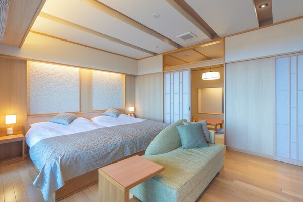 Habitación de hotel con una cama grande, un sofá, una mesita y una puerta corrediza.