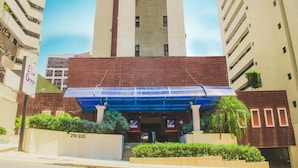 A hotel entrance with a blue canopy, a brick facade, and a sign indicating room numbers 216/222. - JOH Blue Ocean Hotel (Fortaleza)