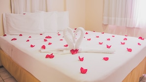 A hotel room with a neatly made bed, white linens, and a heart-shaped towel arrangement on the bed. - JOH Blue Ocean Hotel (Fortaleza)
