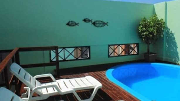 A rooftop pool area with a blue pool, white lounge chairs, and a wall with two fish decorations. - JOH Blue Ocean Hotel (Fortaleza)