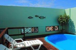 A rooftop pool area with a blue pool, white lounge chairs, and a wall with two fish decorations. - Joh Blue Ocean Hotel (Fortaleza)