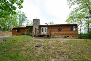 A log cabin with a stone chimney, a wooden deck, and a star decoration on the wall. - Above the Rest: 🏔 View•Hot Tub•Nearby Attractions (Sevierville)