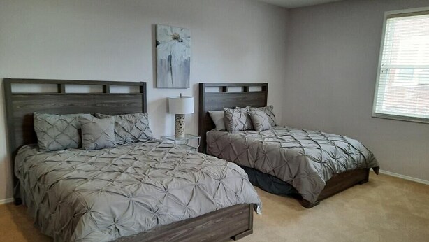 Un dormitorio con dos camas, una mesita de noche, una lámpara y un cuadro en la pared.