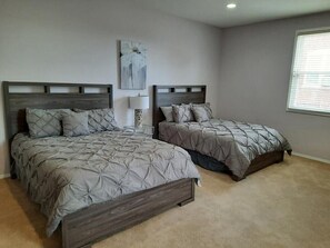 A bedroom with two beds, a nightstand, a lamp, and a painting on the wall.