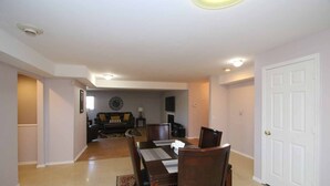 Un comedor con una mesa y sillas de madera, un sofá y un televisor al fondo.