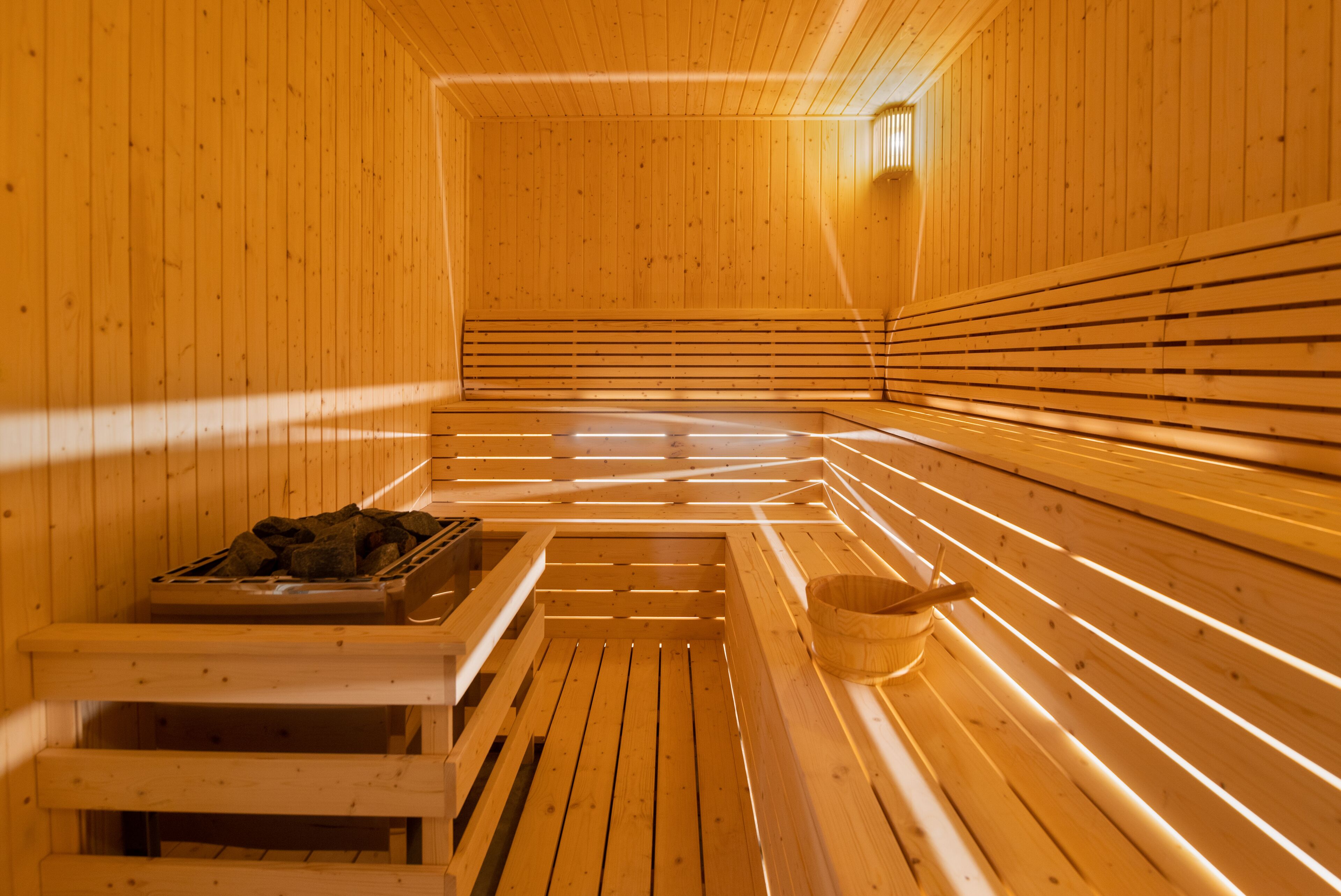 A sauna with wooden benches and a bench with a bucket.