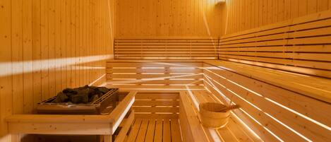 Een sauna met houten banken en een emmer op een bank.