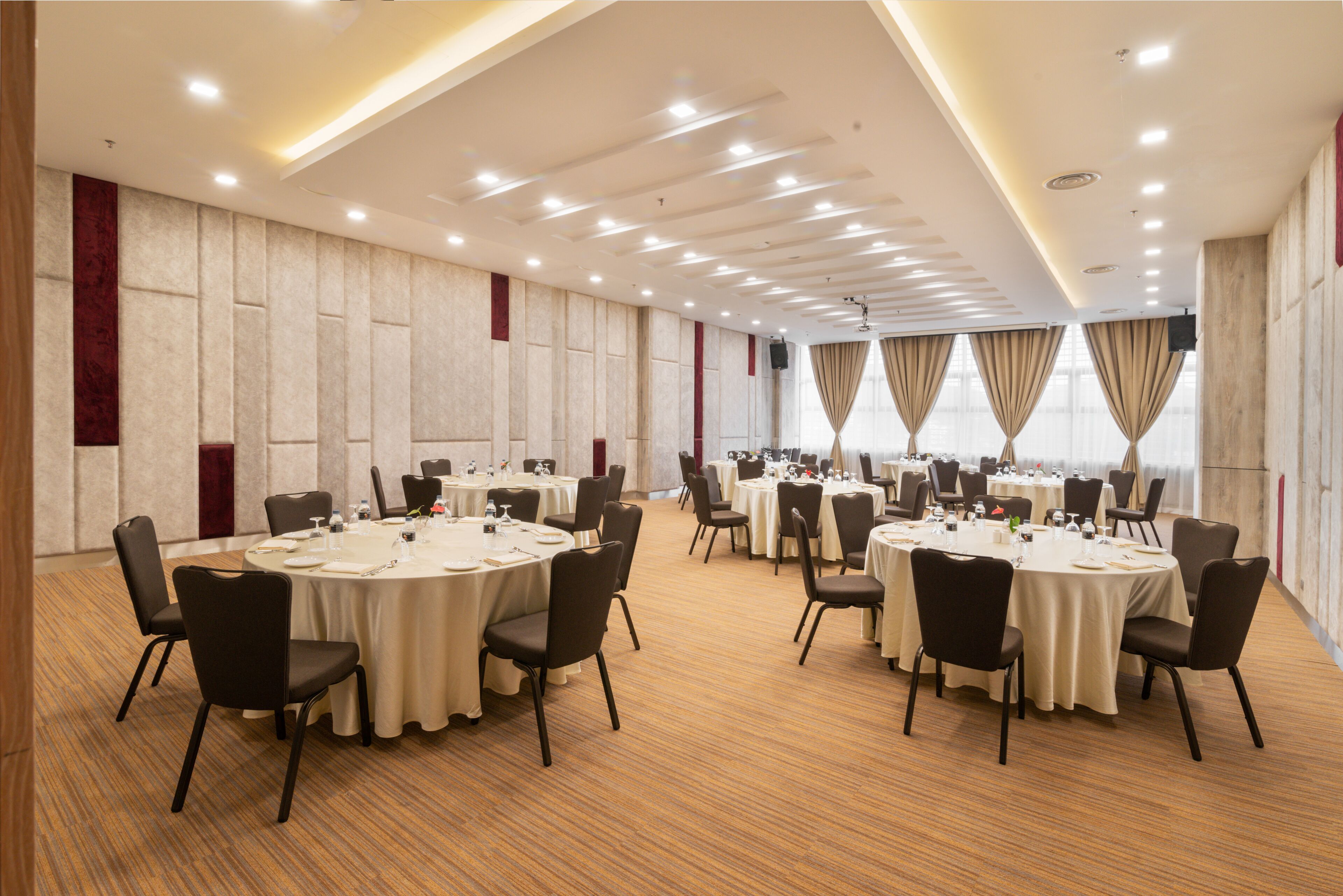 A conference room with multiple round tables, chairs, and a wooden floor.
