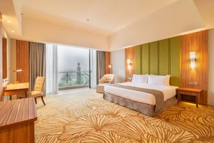 Habitación de hotel con una cama grande, un escritorio, una silla y vistas al exterior.