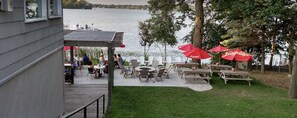 An outdoor patio with tables and chairs, a fire pit, and red umbrellas.