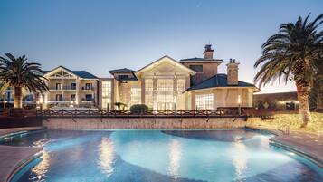 A large hotel with a swimming pool, multiple guest rooms, and a well-maintained outdoor area.