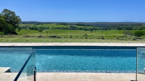 Ein Schwimmbecken mit freiem Blick auf eine grüne Landschaft im Hintergrund.