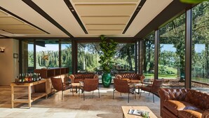 Un vaste espace salon avec des canapés en cuir, une table basse en bois et un grand vase vert.