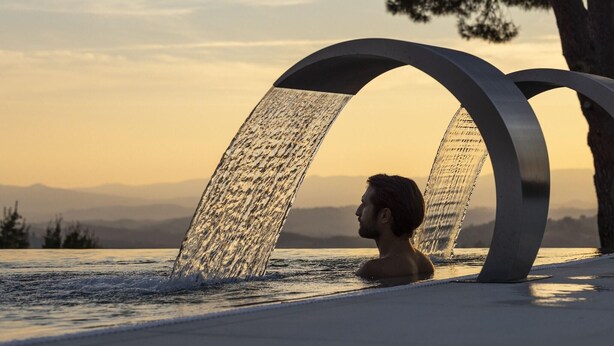 Une personne dans une fontaine ou un bassin, avec un coucher de soleil en arrière-plan.