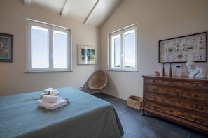 A bedroom with a bed, a dresser, a chair, and two windows. - Villa Cherry Garden (Alassio)