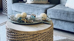 A living room with a grey sofa, a round wicker coffee table, and decorative pillows. - 2 Bedroom Ocean Jeep  (Kihei)