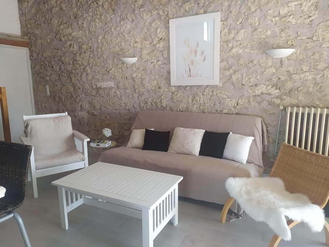 A living room with a stone wall, a beige sofa, a white coffee table, and a white armchair.