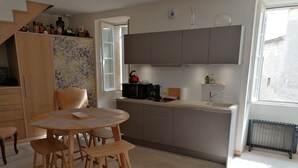 A modern kitchen with a dining area, wooden furniture, and a patterned rug. - Maison au Cœur de Saint-emilion (Saint-Émilion)