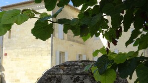 A stone structure with a stone wall and a building in the background. - Maison au Cœur de Saint-emilion (Saint-Émilion)