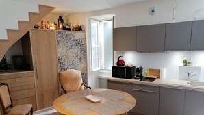 A modern kitchen with grey cabinets, a round wooden table, and a chair. - Maison au Cœur de Saint-emilion (Saint-Émilion)