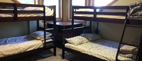 Une chambre de dortoir avec des lits superposés, une petite table et des fenêtres.