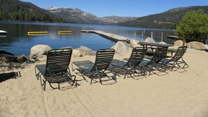 Un cadre idyllique au bord du lac, avec une plage de sable, des chaises longues et une table.