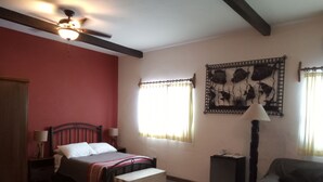 A bedroom with a bed, bedside tables, a bench, a chair, a lamp, a ceiling fan, and a wall-mounted decoration. - Room #6 Master with one king size bed, one double bed & one double bunk bed (La Ribera)