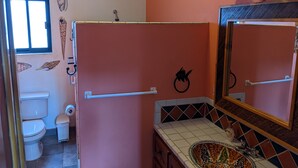 A bathroom with a toilet, a sink with a decorative bowl, a shower curtain, and a mirror with a towel rack. - Room #6 Master with one king size bed, one double bed & one double bunk bed (La Ribera)