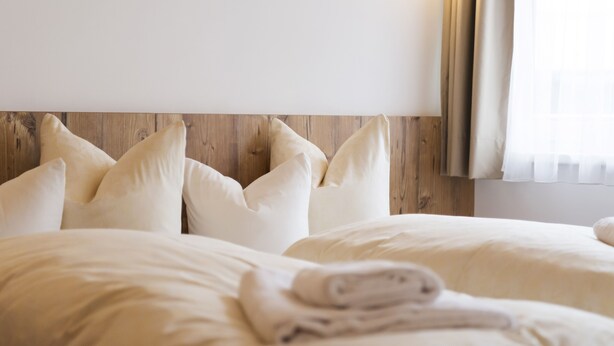 A hotel room with two beds, white bedding, a wooden headboard, and a window with curtains. - Hotel Gabl by Alpeffect Hotels (Sankt Anton am Arlberg)