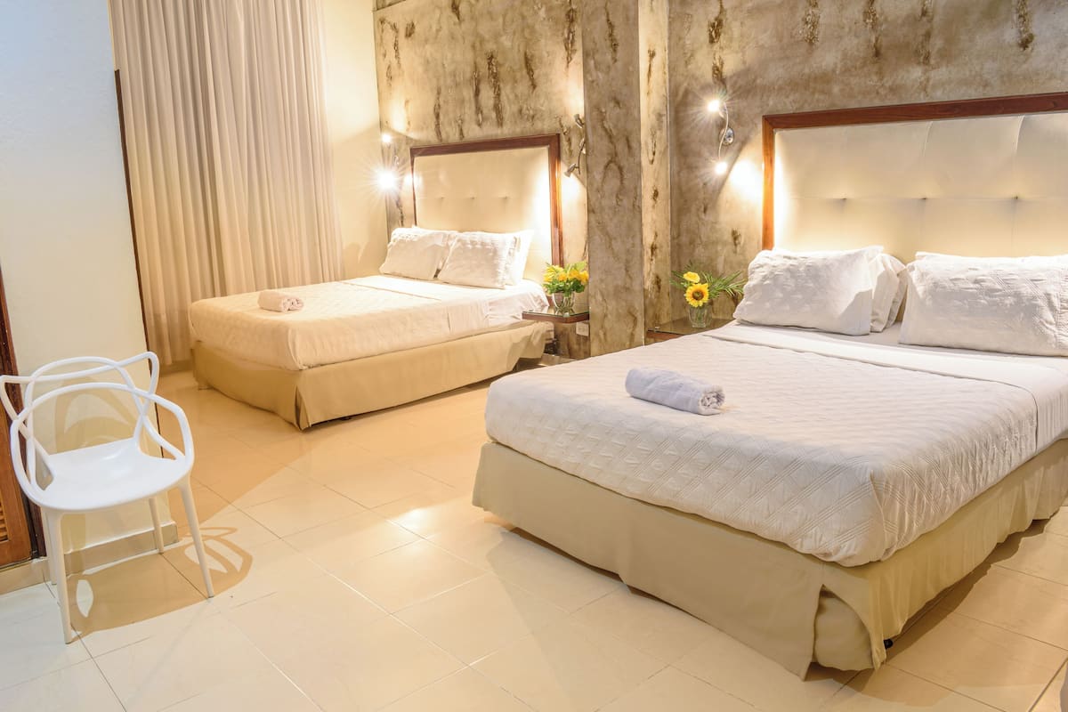 A hotel room with two beds, a white chair, and a marble wall.
