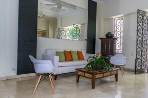 A living room with a white sofa, two white chairs, a wooden coffee table, and a potted plant. - Hotel Virrey Cartagena (Cartagena)