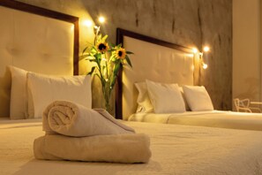 A neatly made bed with a rolled towel, a vase with sunflowers, and a chair in a room with a wooden headboard and soft lighting.