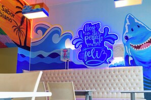 A room with a large, colorful mural, a neon sign, and a tufted headboard.