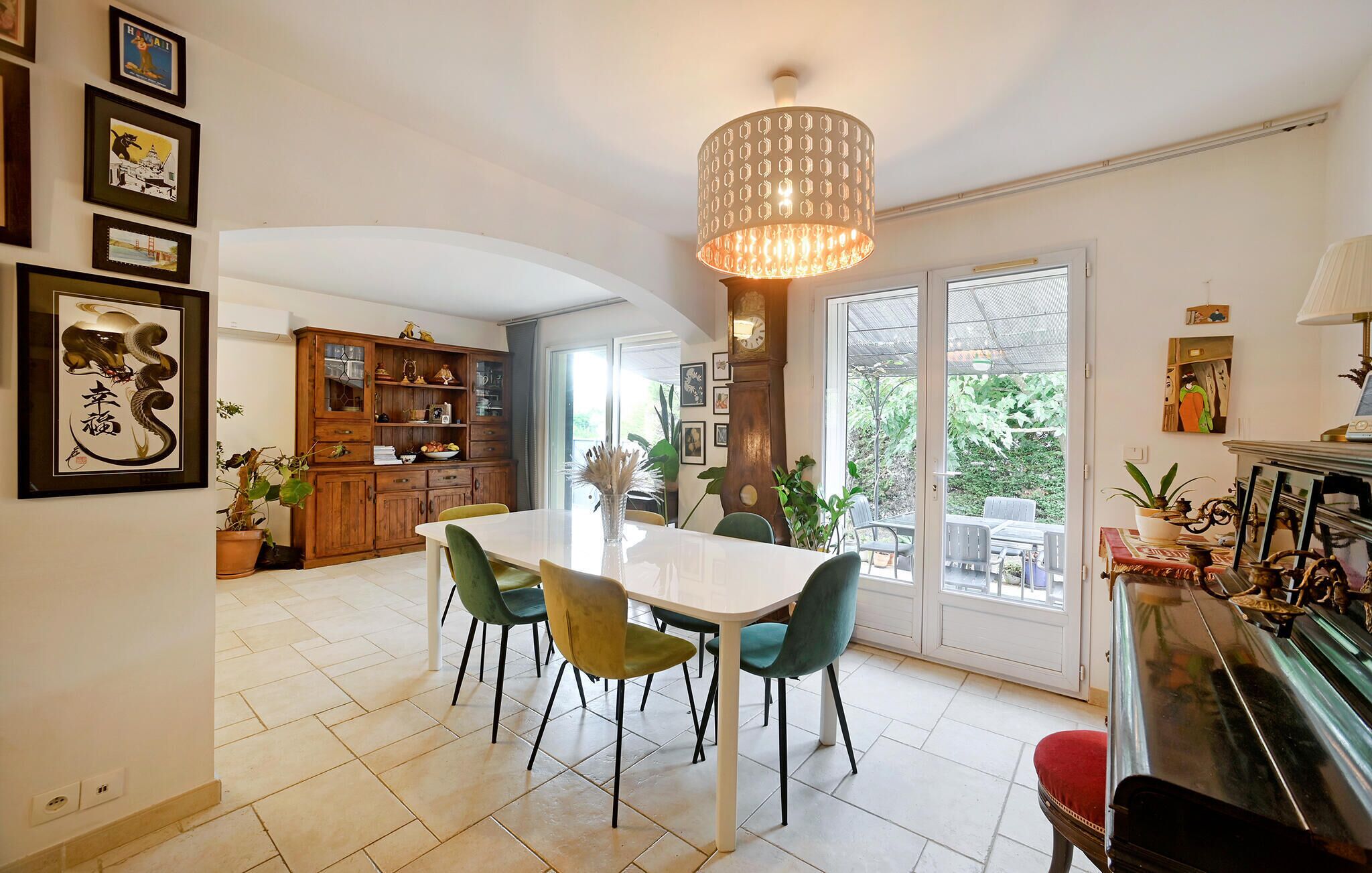 A spacious dining area with a white table and chairs, a large wooden cabinet, and a hanging light fixture.