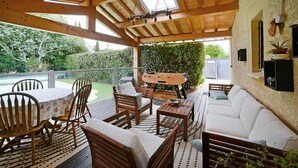 Une terrasse extérieure couverte, aménagée avec des meubles en bois, un canapé blanc et une table.