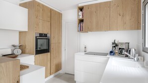 Ett modernt kök med träskåp, en inbyggd ugn, en diskho och en kaffemaskin.