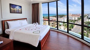 A hotel room with a large window, a bed with white bedding, and a framed picture on the wall. - Sunflower Hotel (Tuy Hoa)