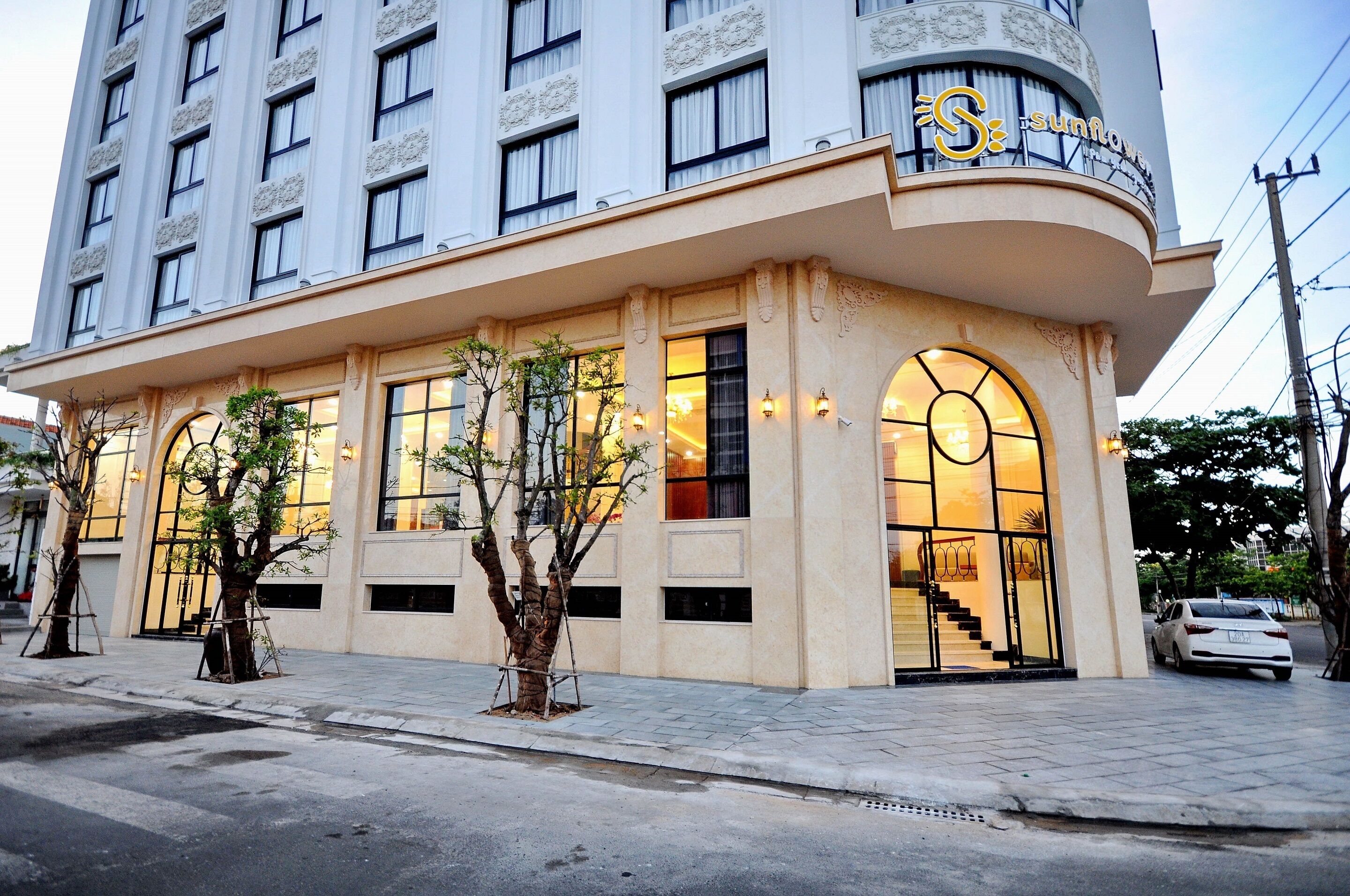 A hotel with a curved facade, large arched windows, and a staircase leading to the entrance.