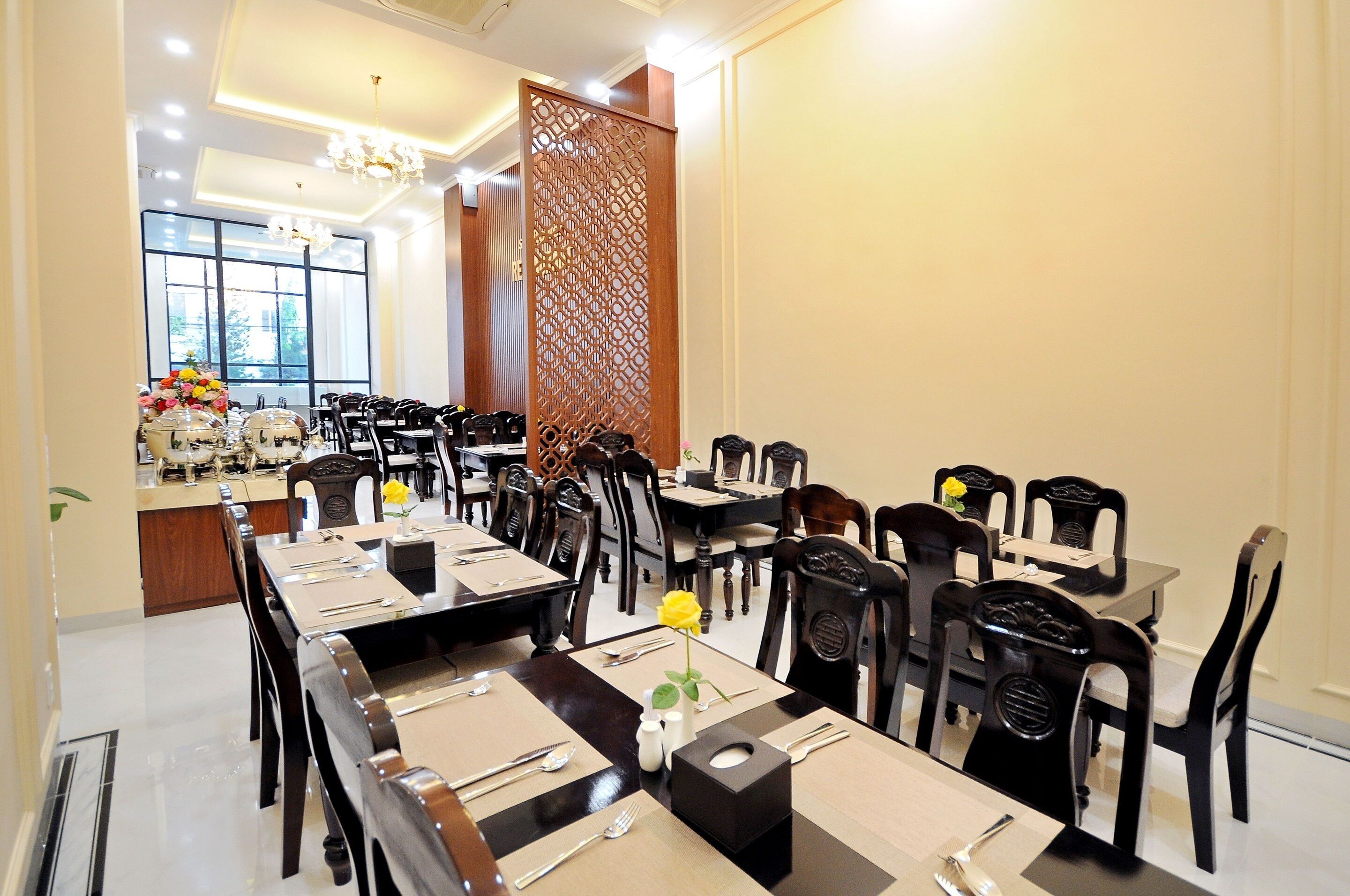 A dining area with multiple tables and chairs, a decorative wooden partition, and a window providing natural light.