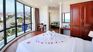 A hotel room with a large window, a bed with a swan towel, a desk, and a view of the city. - Sunflower Hotel (Tuy Hoa)
