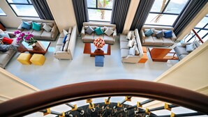 A spacious living area with multiple sofas and a coffee table, large windows with curtains, and a staircase with a marble floor. - Sunflower Hotel (Tuy Hoa)