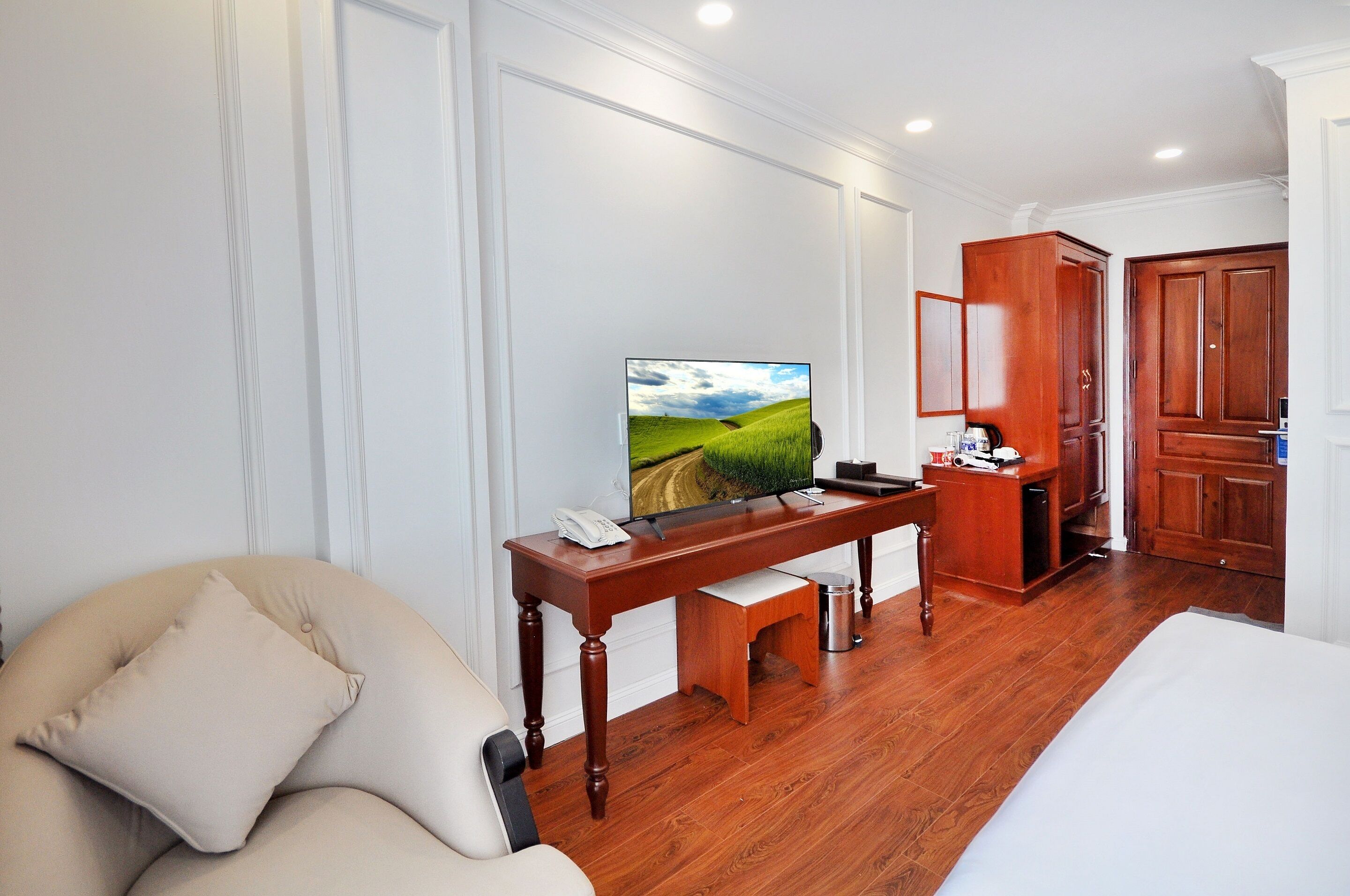 A hotel room with a wooden desk, a television, a sofa, and a bed.