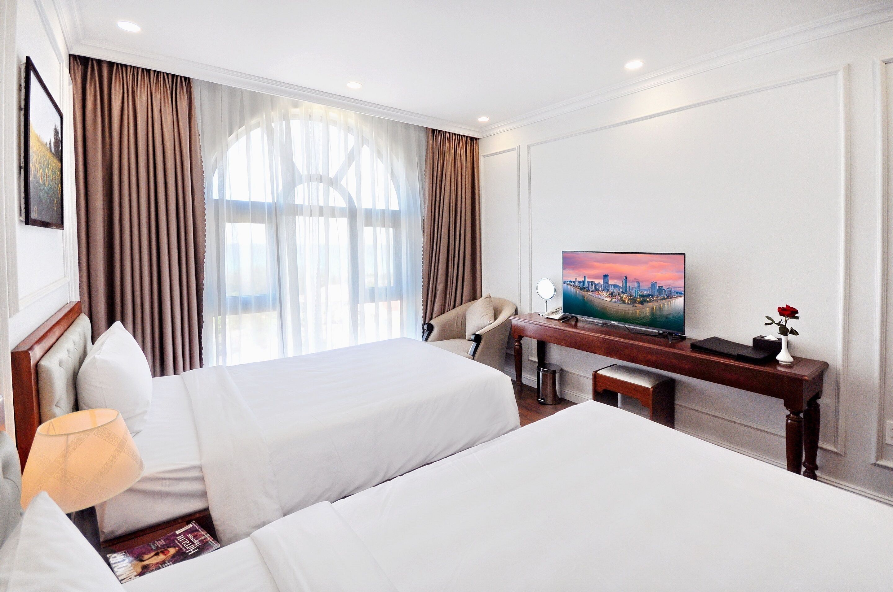 Une chambre d’hôtel avec deux lits, une télévision, un bureau et une chaise.
