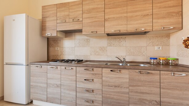 Une cuisine moderne avec des meubles en bois, une cuisinière à gaz encastrée et un évier en acier inoxydable.